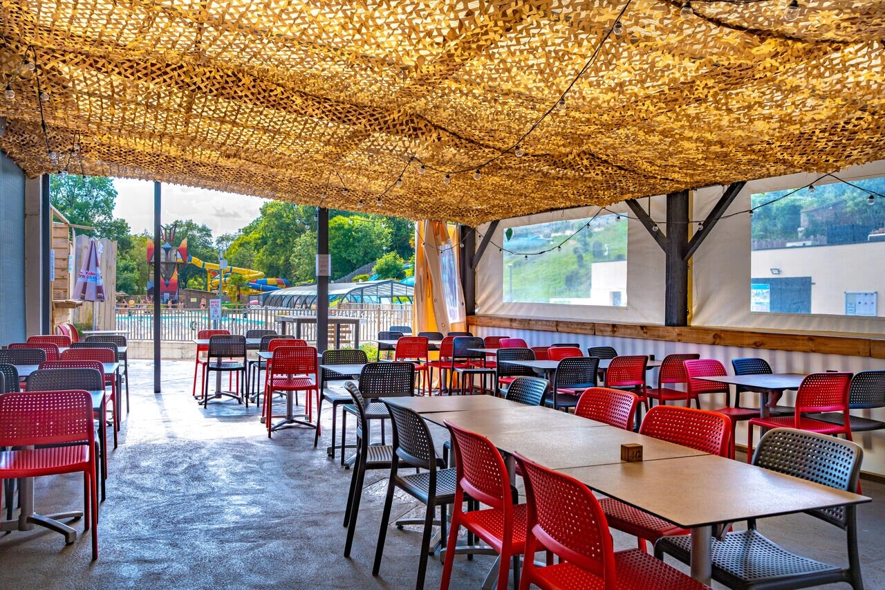 Terrasse restaurant ombrag�e, tables, chaises, piscine au camping CAPFUN La Rivi�re � Valence-en-Poitou (86).