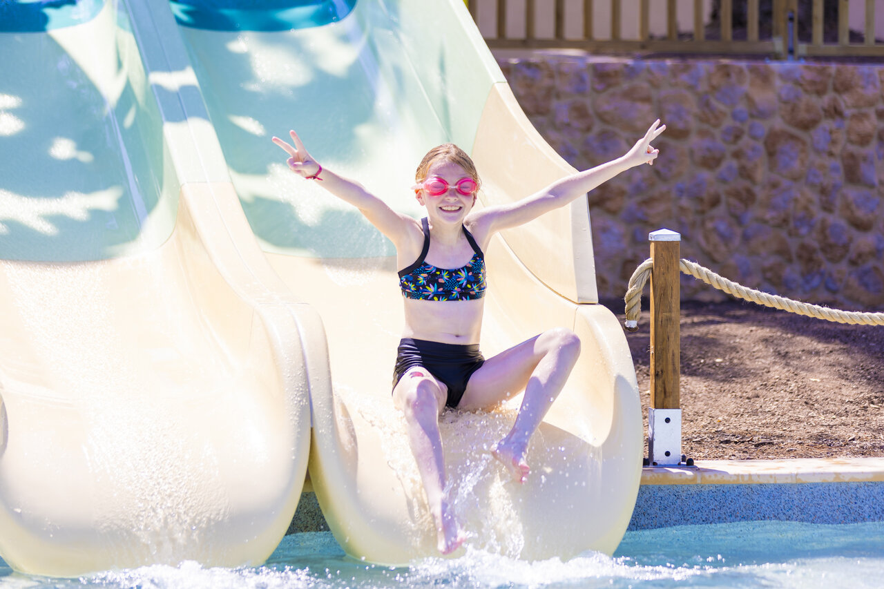 Fille souriante descendant un toboggan aquatique dans la piscine au camping CAPFUN La Rumba � Fr�jus (83).
