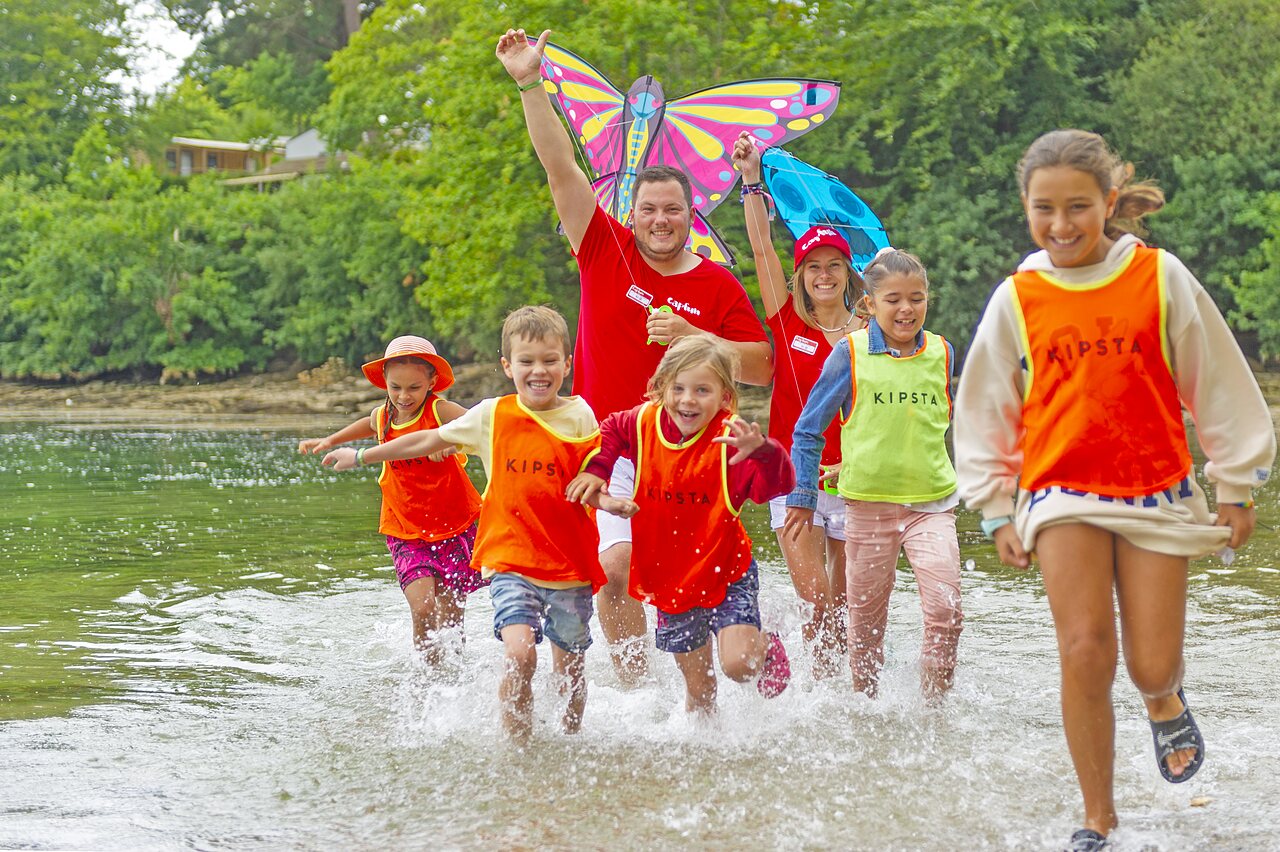 Enfants et animateurs jouant dans l'eau avec un cerf-volant au camping CAPFUN Saint Laurent � LA FORET FOUESNANT (29).