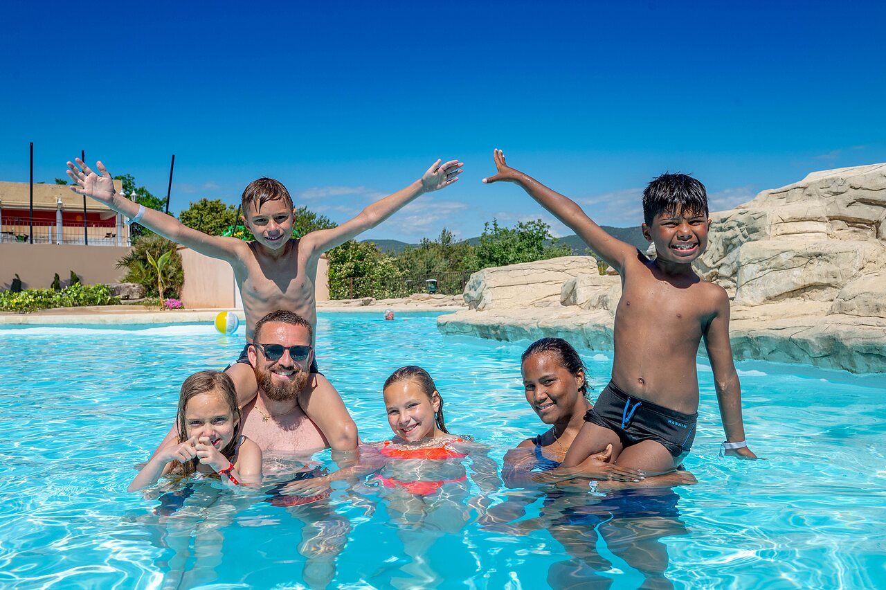 Famille souriante profitant de la piscine ext�rieure au camping VAGUES OCEANES Soleil de Provence.