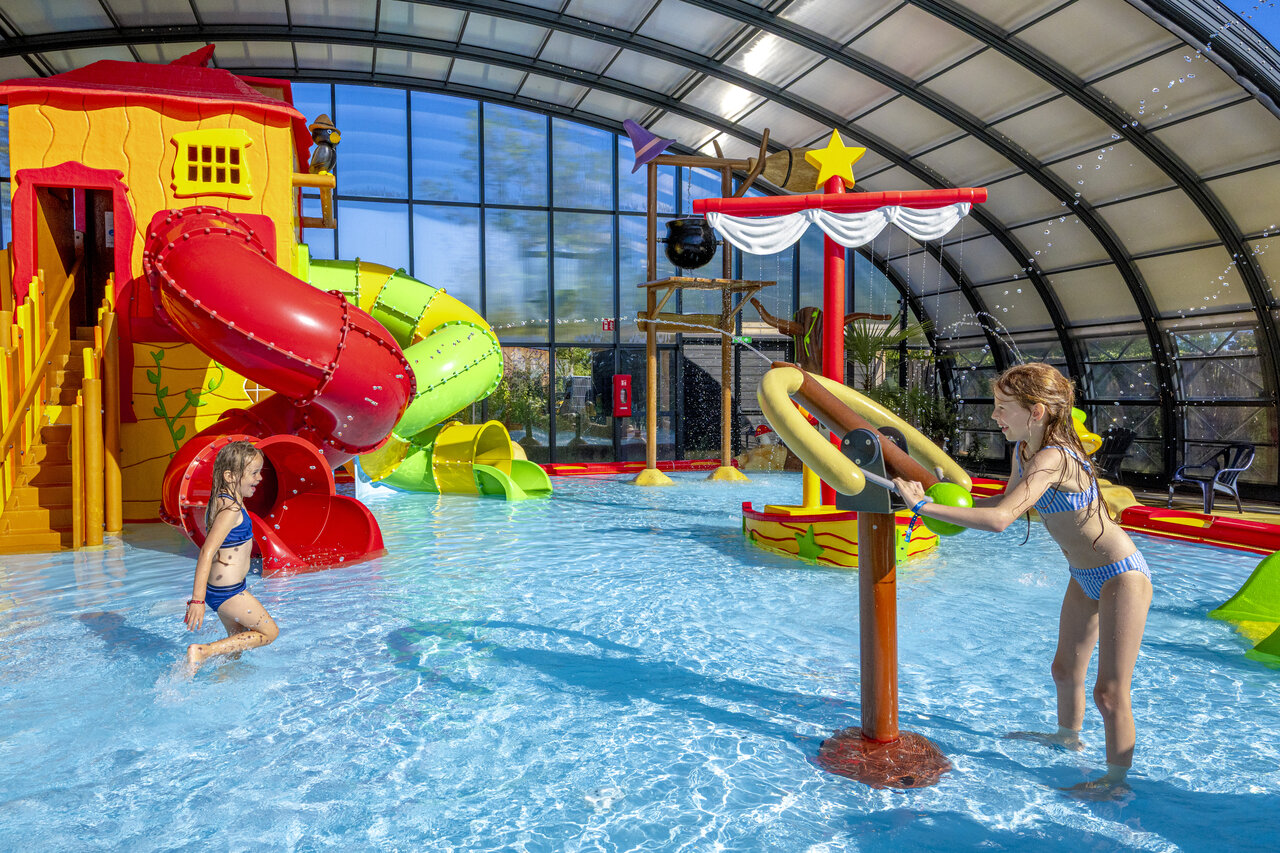 Enfants s'amusant dans la piscine couverte avec toboggans au CAPFUN De Sprookjescamping � Rheeze.