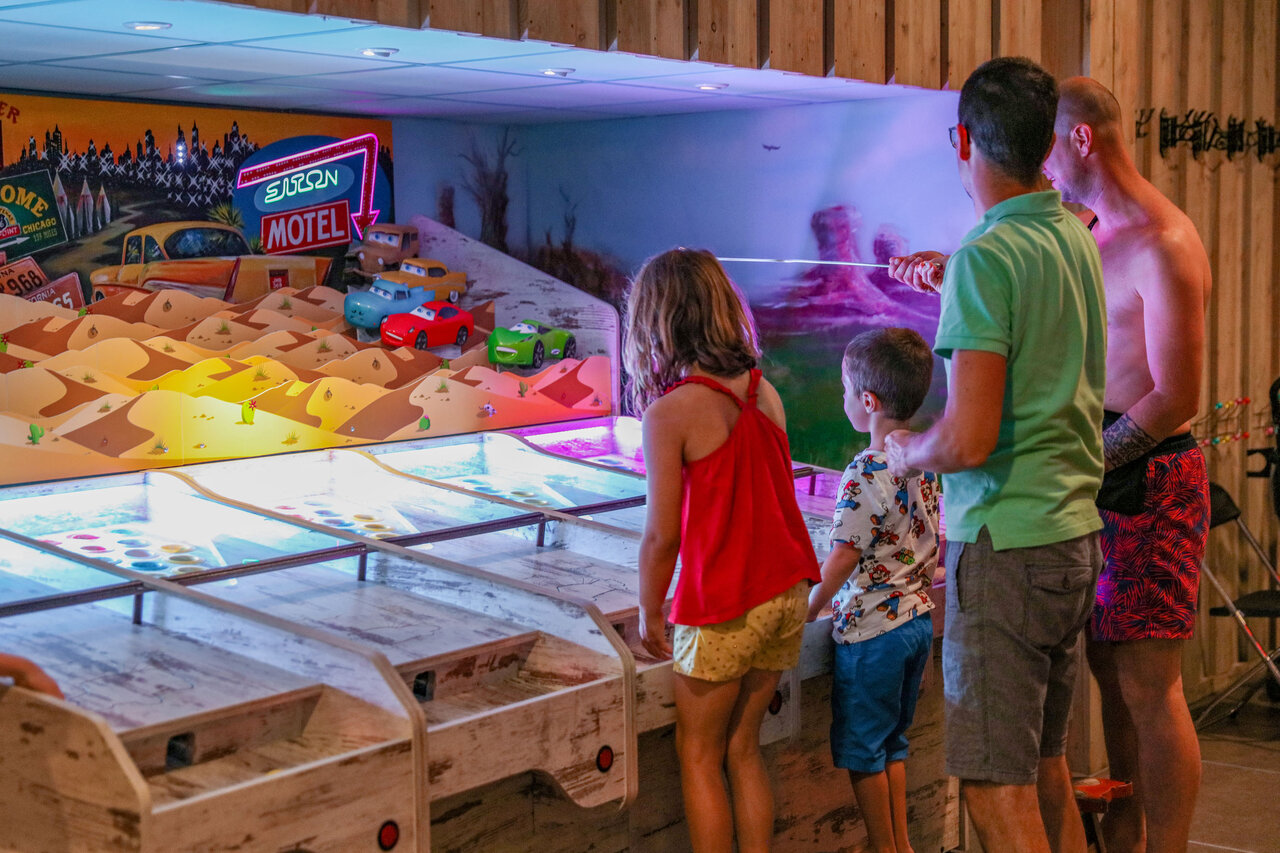 Famille jouant � un jeu d'arcade int�rieur au camping CAPFUN De Sprookjescamping � Rheeze.