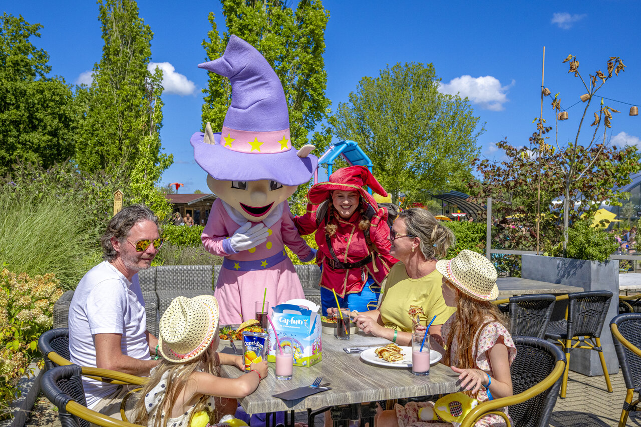 Famille d�nant avec mascottes et animateurs au camping CAPFUN De Sprookjescamping � Rheeze.
