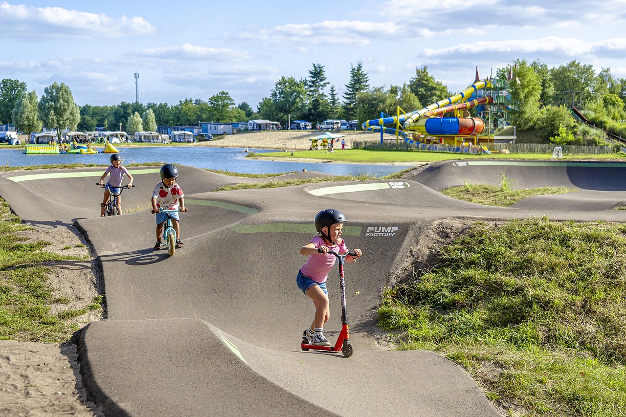 Enfants sur pump track avec v�los et trottinette au CAPFUN Vakantiepark het Stoetenslagh.