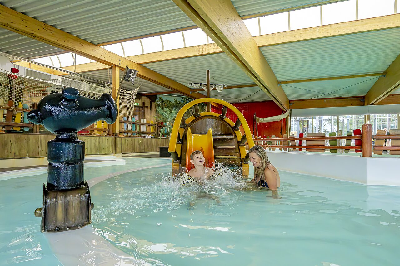 Enfant et femme riant sur toboggan aquatique pirate dans piscine int�rieure au camping CAPFUN Vakantiepark Capfun het Stoetenslagh � Rheezerveen.