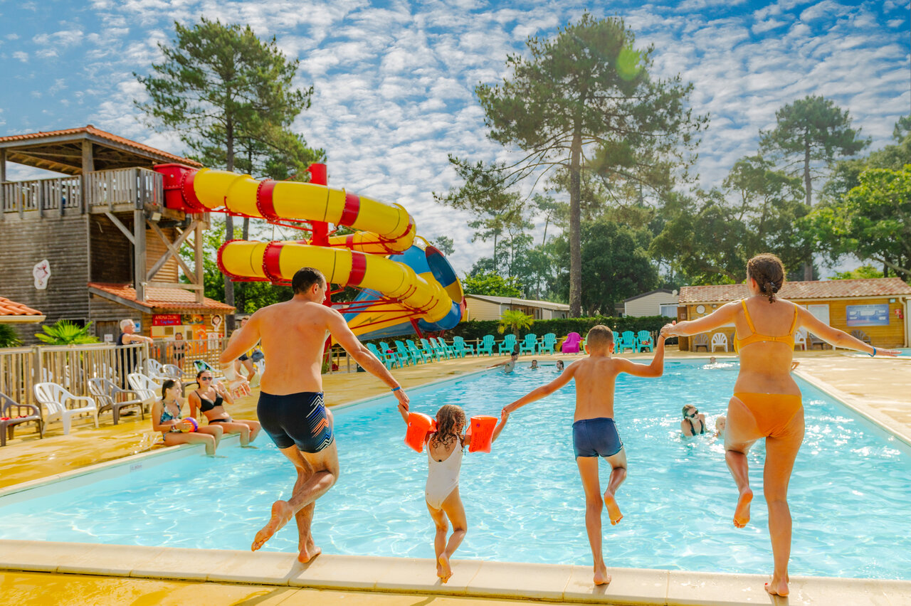 Famille sautant dans la piscine avec toboggans g�ants au camping CAPFUN Sud Land � Labenne-Ocean.