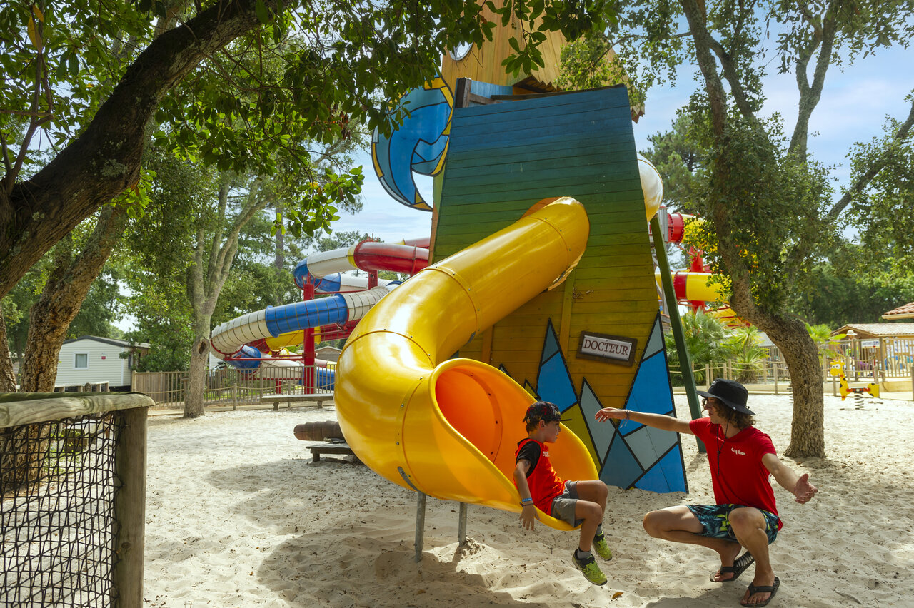 Toboggan jaune et enfant jouant avec animateur au camping CAPFUN Sud Land � Labenne-Ocean.