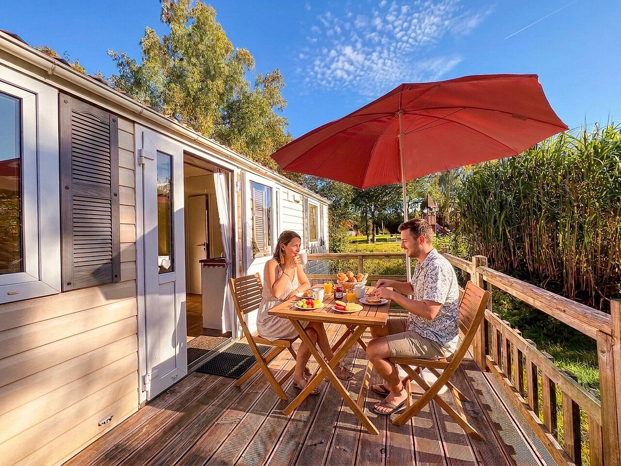 Mobil-home avec terrasse en bois, couple d�jeunant au camping CAPFUN Tecklenburg � Tecklenburg-Leeden.
