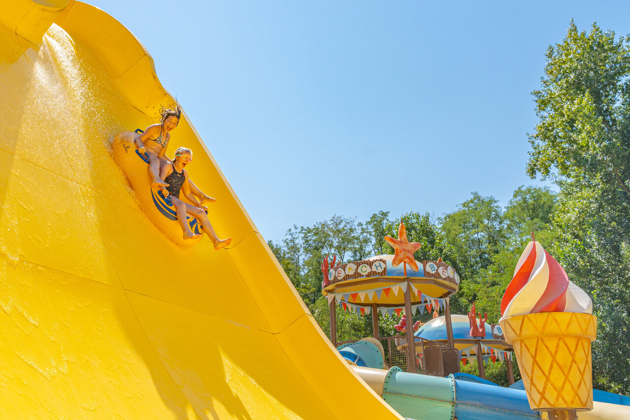 Enfants d�valant un grand toboggan aquatique jaune au camping CAPFUN Temps Libre � BOUGE CHAMBALUD (38).