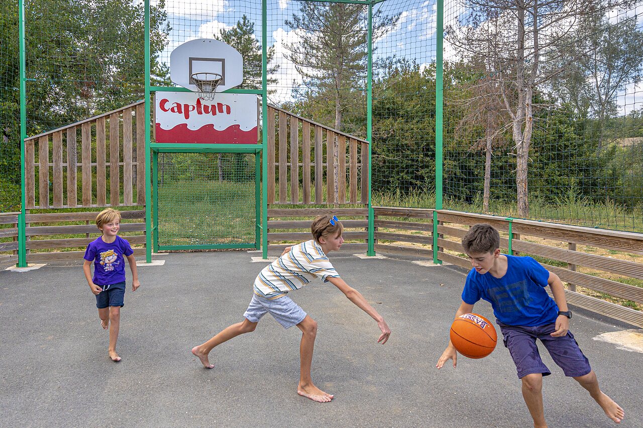 Terrain de basketball ext�rieur avec jeunes joueurs au camping CAPFUN Ullule (47).