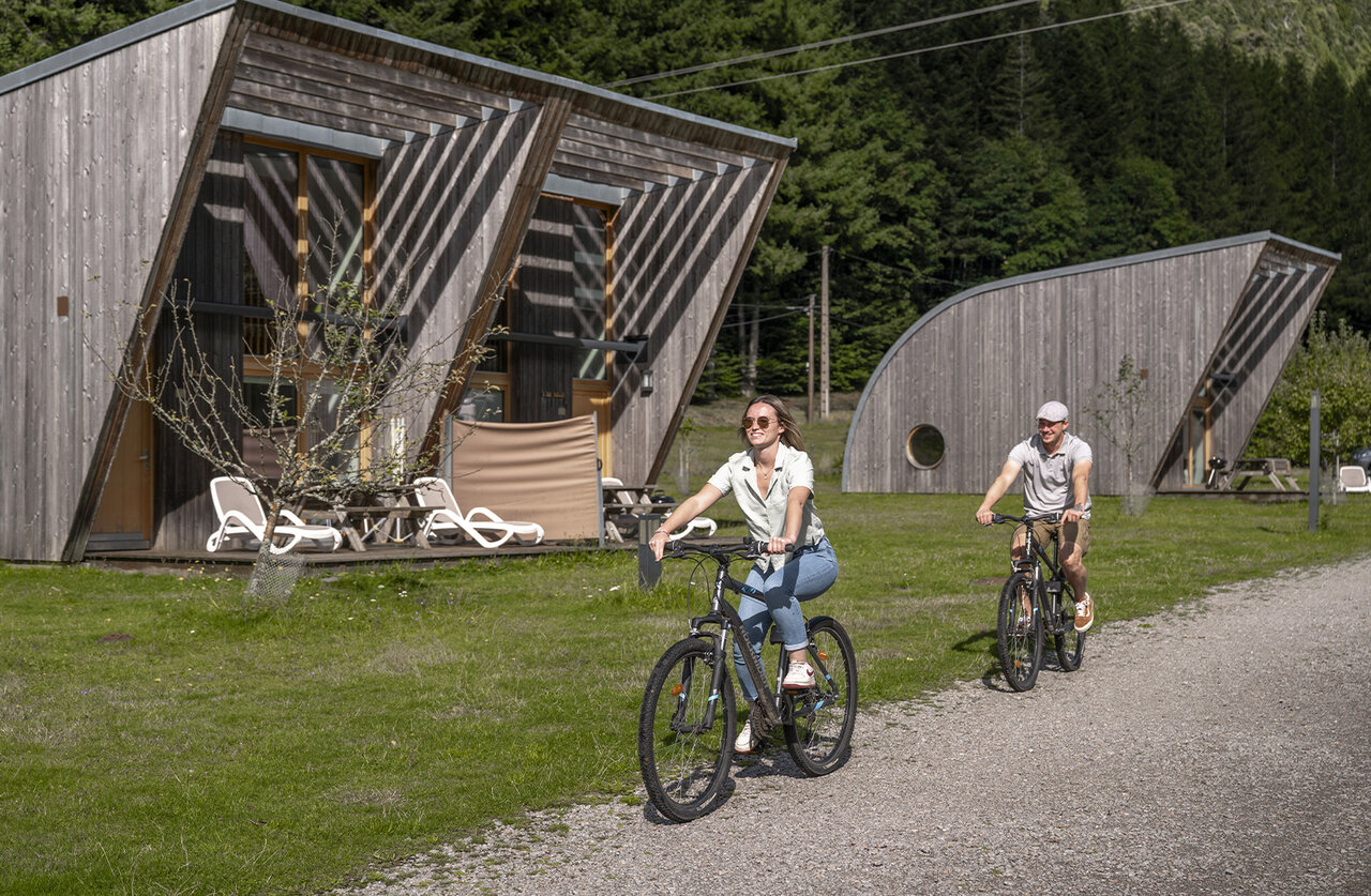 Koppel op de fiets voor moderne Mobil-homes op camping CLICOCHIC Verte Vall�e in XONRUPT LONGEMER (88).
