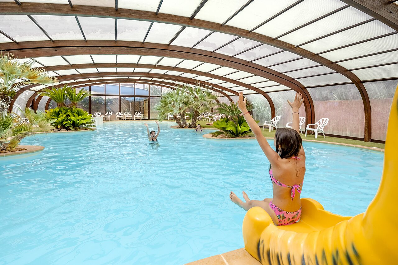 Piscine couverte avec toboggan et enfants jouant au camping CAPFUN Vignes d'Or � Serignan.