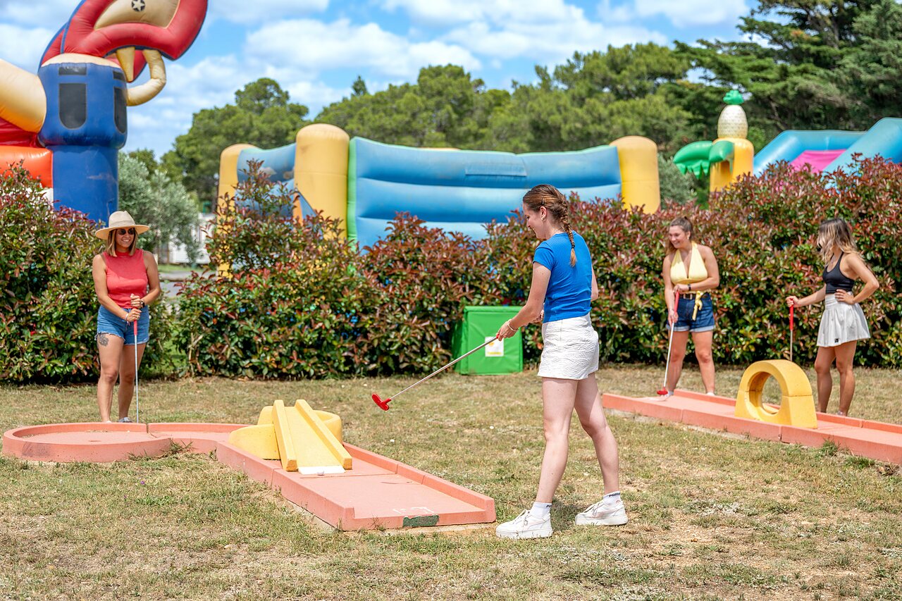 Femmes jouant au mini-golf avec jeux gonflables au camping CAPFUN Vignes d'Or � Serignan.