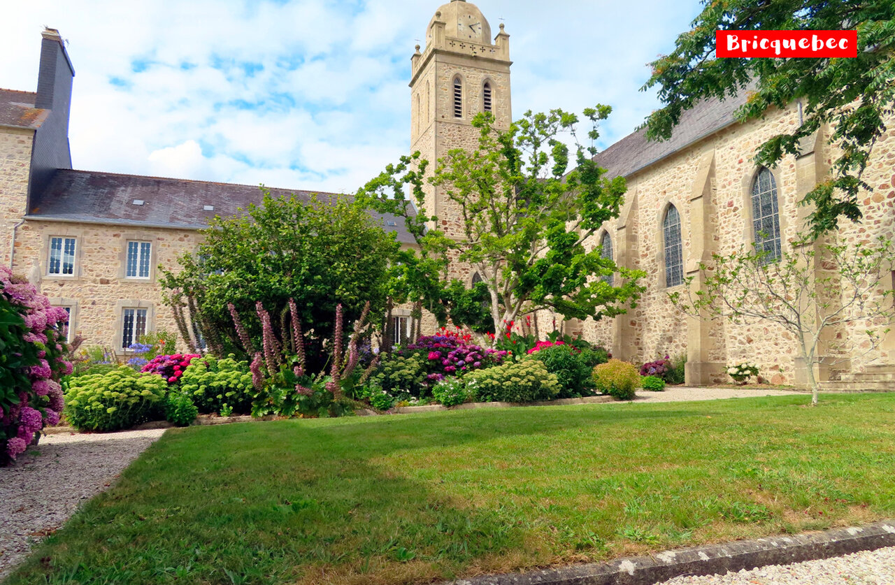 �glise historique avec clocher et jardins fleuris � Bricquebec, Normandie.