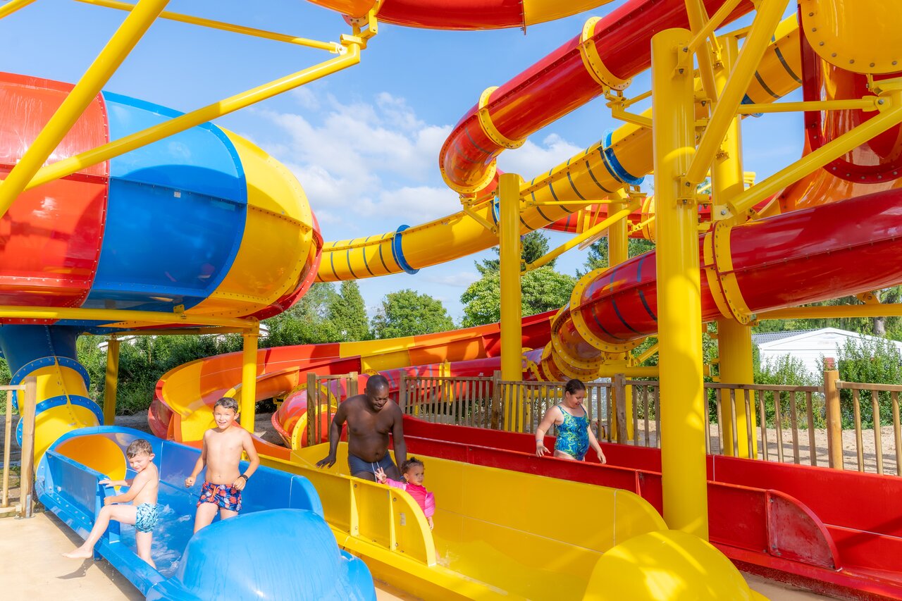Colorful water slides and family having fun at CAPFUN Le Village Parisien campsite in VARREDDES (77).
