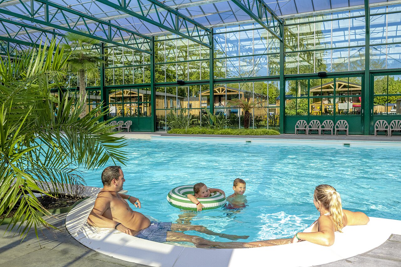 Famille profitant de la piscine couverte avec Mobil-homes au camping CAPFUN Vlinderloo � Enschede.