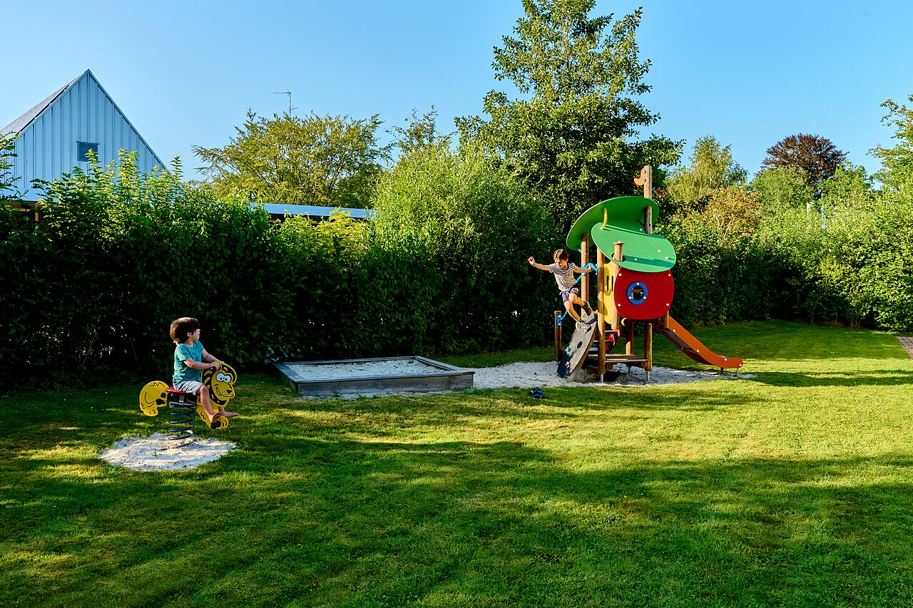 Aire de jeux avec toboggan, structure d'escalade et enfant sur jeu � ressort au camping CAPFUN De Waldsang � Bakkeveen.