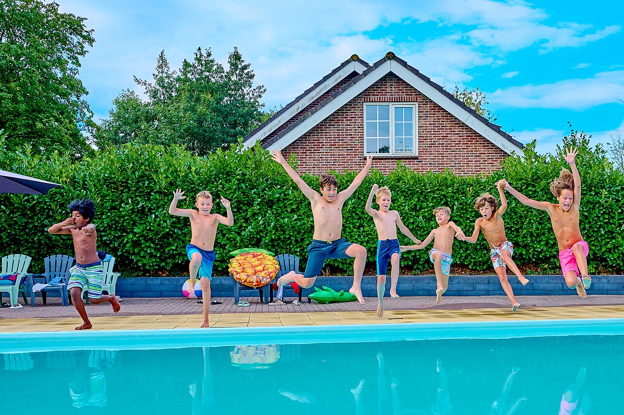 Enfants sautant joyeusement pr�s de la piscine ext�rieure au camping CAPFUN Wieskamp � Winterswijk Henxel.