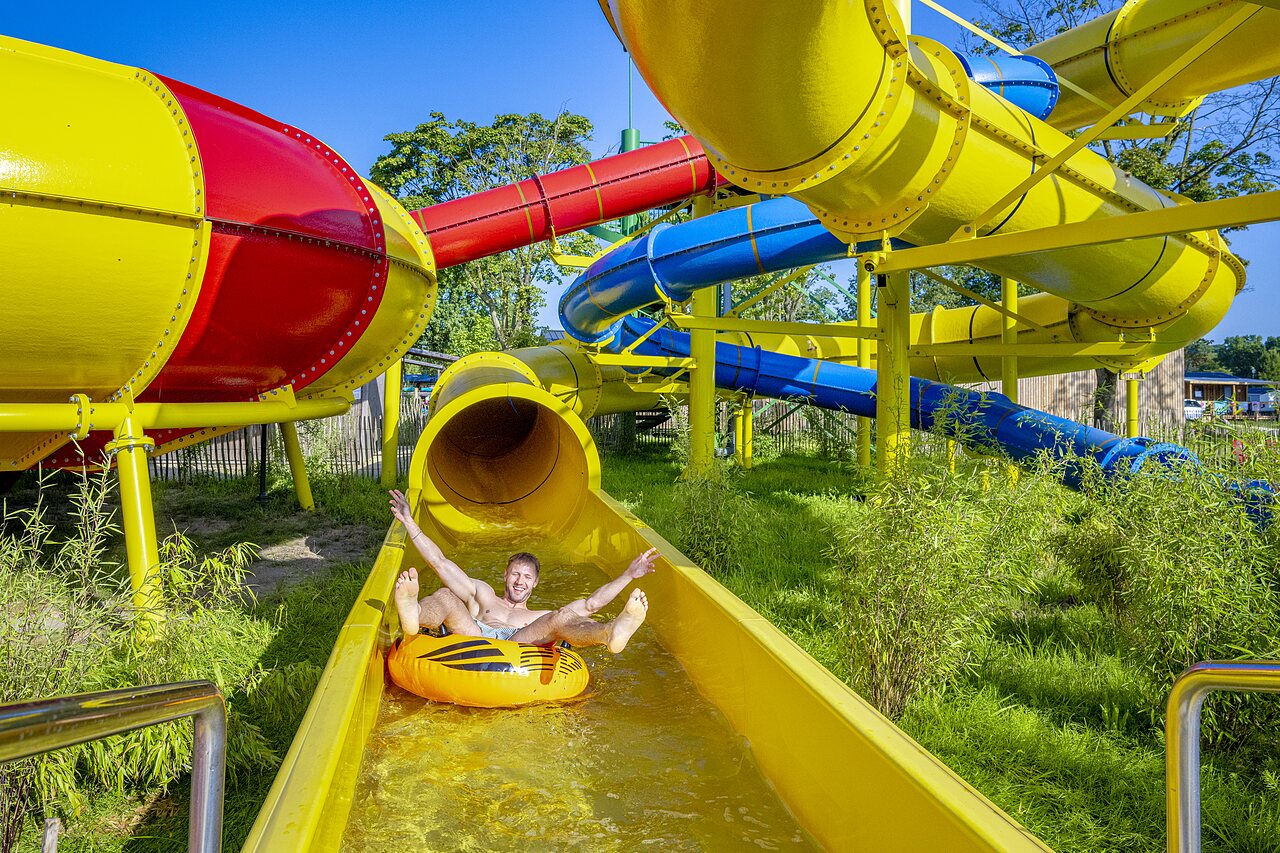 Homme sur bou�e dans toboggan aquatique color� au camping CAPFUN de Wondermolen � Molenschot.