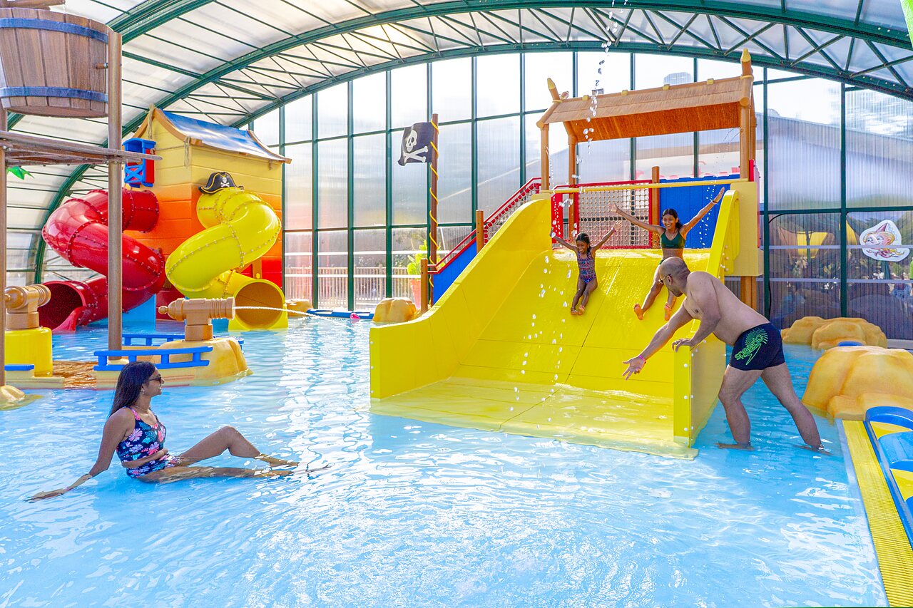 Piscine couverte avec toboggans et jeux aquatiques, famille s'amusant au camping CAPFUN Zagarella � LONGEVILLE SUR MER (85).